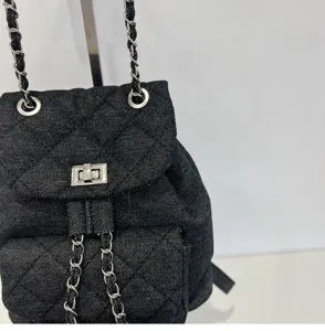 Detailed view of the black quilted denim backpack with silver chain straps and chic turn-lock.