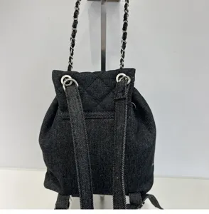 Black denim quilted bucket backpack with metal chain straps, stylish everyday casual bag.