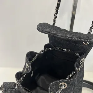 Close-up detail of black denim quilted bucket backpack with chain strap and flap closure.