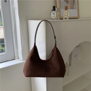 Close-up detail of the brown plush hobo underarm bag showcased in a minimalist white room.
