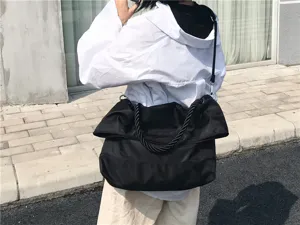 Λεπτομερής όψη της μαύρης τσάντας ώμου με λαβή από σχοινί και μαλακό πτυσσόμενο σχεδιασμό.