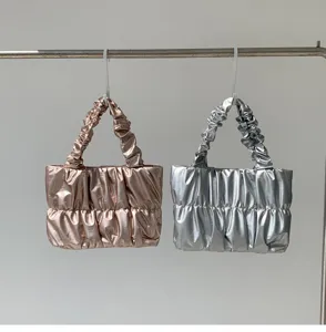 Detailed view of fashionable metallic pleated cloud tote bag featuring elegant ruffled handles.