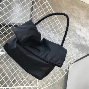 Λεπτομερές κοντινό πλάνο μαύρης νάιλον τσάντας ώμου με πλεγμένη λαβή από σχοινί.