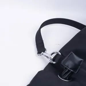 Κοντινή λήψη λεπτομέρειας μαύρης νάιλον τσάντας χειρός με μεταλλικό κούμπωμα και λουράκι.