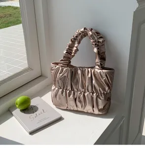 Close-up detail of stylish metallic ruched cloud handbag, elegant texture and design.