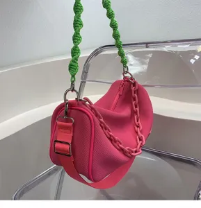 Pink barrel handbag with green woven strap, stylish underarm shoulder bag for summer daily commute.