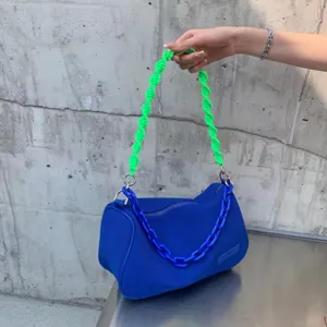 Blue canvas underarm shoulder bag with neon green braided handle and chic chain accessory.