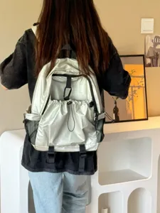 Vue détaillée d'un sac à dos argenté élégant et imperméable avec de multiples poches pratiques.