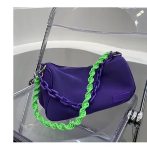 Purple underarm bag detail, featuring green woven strap and purple chain link accent.