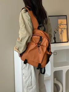 Gros plan du sac à dos de banlieue orange montrant plusieurs poches et sangles.