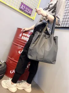 Grey nylon tote bag detail, featuring drawstring closure and durable shoulder straps for daily use.