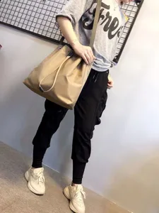 Detailed shot of casual nylon shoulder bag worn by model, showing large capacity and strap.