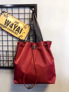 Wine red nylon drawstring tote bag detail, featuring durable shoulder straps and casual style.
