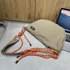 Oversized nylon dumpling crossbody bag with trendy orange rope knots for casual daily use.