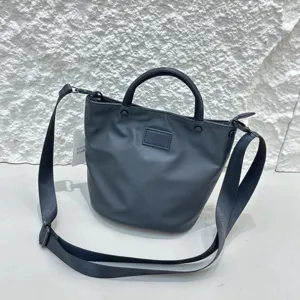 Close-up detail shot of black nylon waterproof bucket bag with adjustable strap and sturdy handle.
