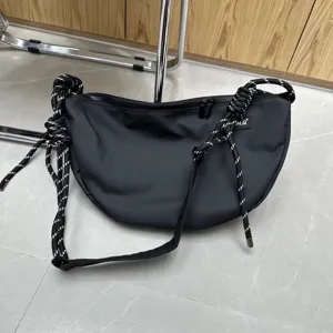 Black oxford cloth crescent crossbody bag with stylish black and white knotted rope details for women.