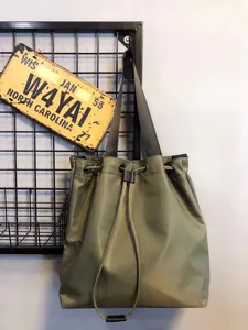 Green nylon bucket shoulder bag, casual tote handbag with drawstring, stylish everyday accessory.