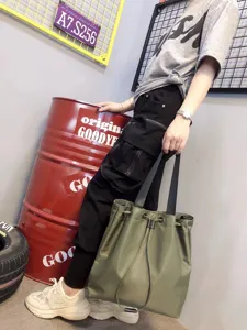 Detail view of the green nylon tote bag, showcasing large capacity and shoulder wear style.