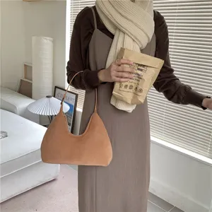 Close-up detail of a soft brown plush hobo shoulder bag worn in a cozy indoor lifestyle setting.