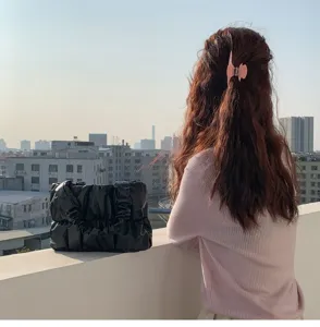 Detail view of the soft gathered cloud bag in black, showcasing daily lifestyle on a rooftop.