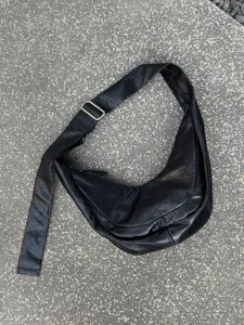 Vue détaillée du sac porté épaule hobo souple en cuir noir avec sangle et boucle métallique.