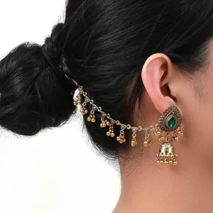 Gros plan de boucles d'oreilles jhumka indiennes vintage avec pierre précieuse verte
