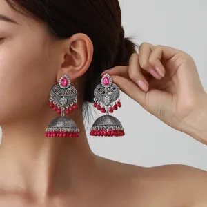 Detail shot of ethnic bohemian carved long tassel jhumka earrings with pink beads.