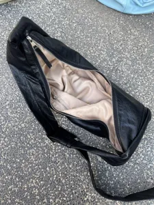 Vue rapprochée détaillée de l'intérieur du sac à épaule en cuir souple noir et de la fermeture.