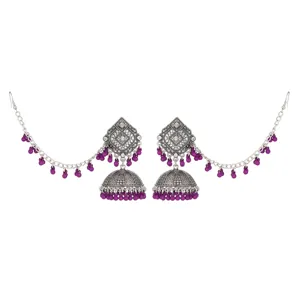 Nahaufnahme traditioneller indischer Jhumka-Ohrringe mit Silberschnitzerei und lila Perlen.