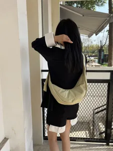 Vue détaillée d'un sac bandoulière souple minimaliste porté en extérieur, style rétro.