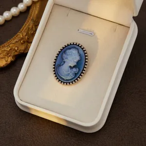 Vintage blue cameo brooch featuring a classic carved profile portrait with beaded metal rim frame.
