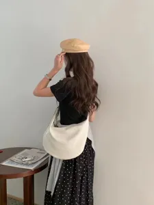 Detailed view of white slouchy dumpling shoulder bag worn in daily casual outfit.