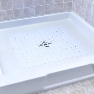 White anti-slip shower mat with suction cups and drain hole inside a clean shower stall.