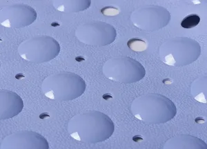 Close-up detail of blue anti-slip bathroom mat surface with textured bumps and drainage holes.