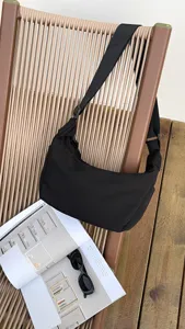 Black nylon crescent crossbody bag, stylish waterproof dumpling shoulder bag with wide strap.