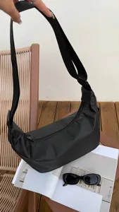 Close-up detail of a black nylon crescent crossbody bag in a casual lifestyle scene.
