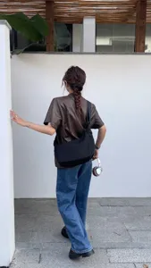 Detailed shot showing the black crescent crossbody bag with wide strap and casual streetwear.