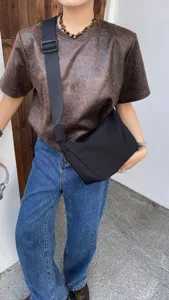Detail view of black crescent crossbody bag, streetwear style with wide strap for women.
