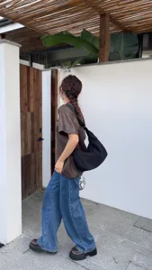 Black canvas crossbody hobo bag detail shot, wide strap casual crescent dumpling bag style.