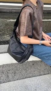Black crescent crossbody bag for women, wide strap nylon shoulder bag, casual street style.
