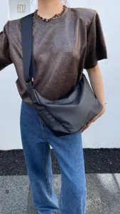 Detailed view of the black crescent crossbody bag featuring a wide strap and streetwear style.
