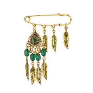 Vintage bohemian gold tone safety pin brooch with green beads and feather pendants for daily wear