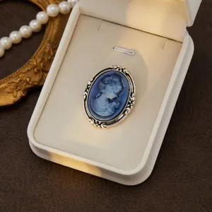 Vintage cameo brooch detail shot, elegant blue portrait in ornate silver box display.