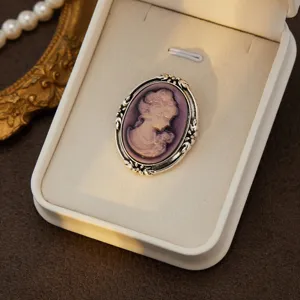 Vintage cameo brooch detail shot, ornate silver frame with purple relief portrait for elegant look