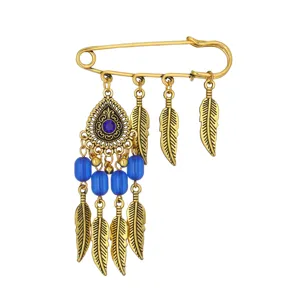 Vintage gold safety pin brooch featuring bohemian style blue beads, feathers, and central crystal.