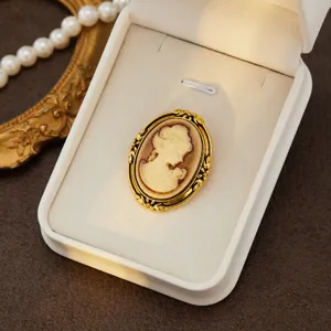 Detailed view of a vintage cameo brooch with golden ornate frame and lady relief in jewelry box.