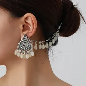 Detailed closeup of bohemian vintage ethnic silver ear cuff hair chain set with white beads.