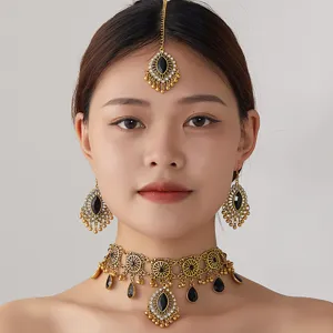Détail en gros plan d'un ensemble de collier ras du cou ethnique doré avec des pierres noires.