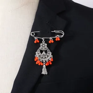 Detailaufnahme der vintage bohemischen Quastenbrosche mit orangen Perlen am schwarzen Revers.