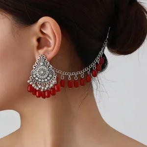 Close-up detail of bohemian vintage silver drop earring and hair chain with red beads.